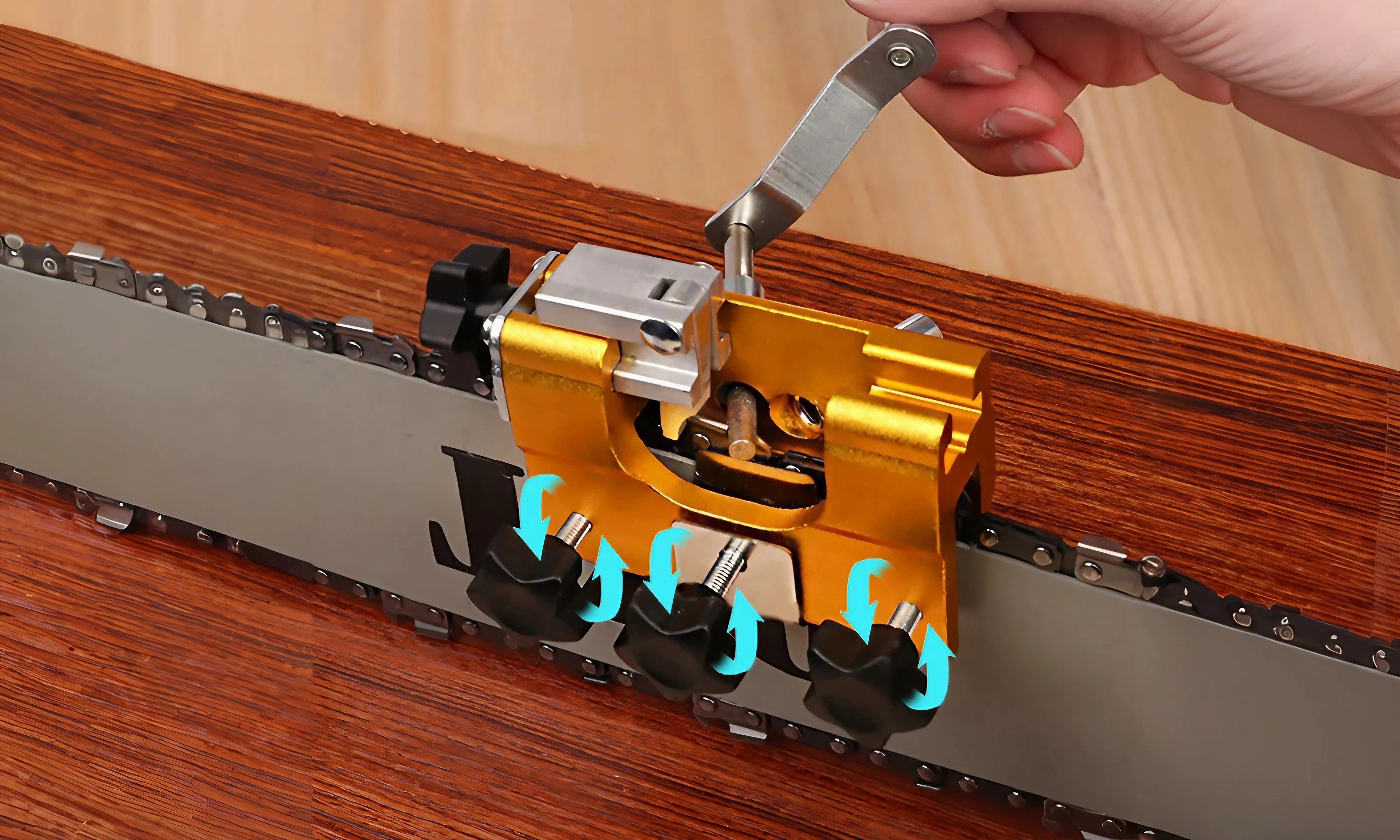 Close-up of the sharpener's three adjustment knobs clamped over a chainsaw bar